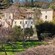 A multi level country manor is surrounded by trees and contains an arched column terrace on the top level